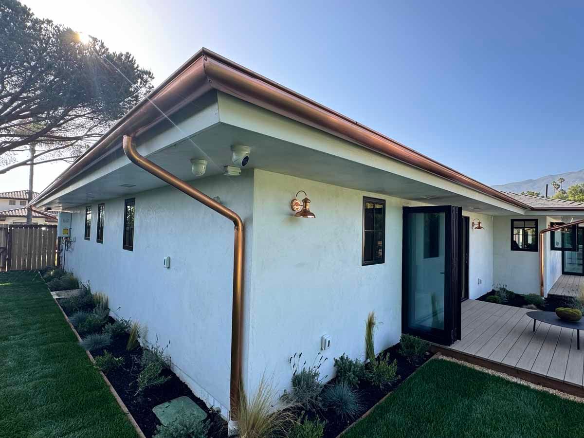 White single-story house exterior with green lawn, brown roof, and a sliding glass door