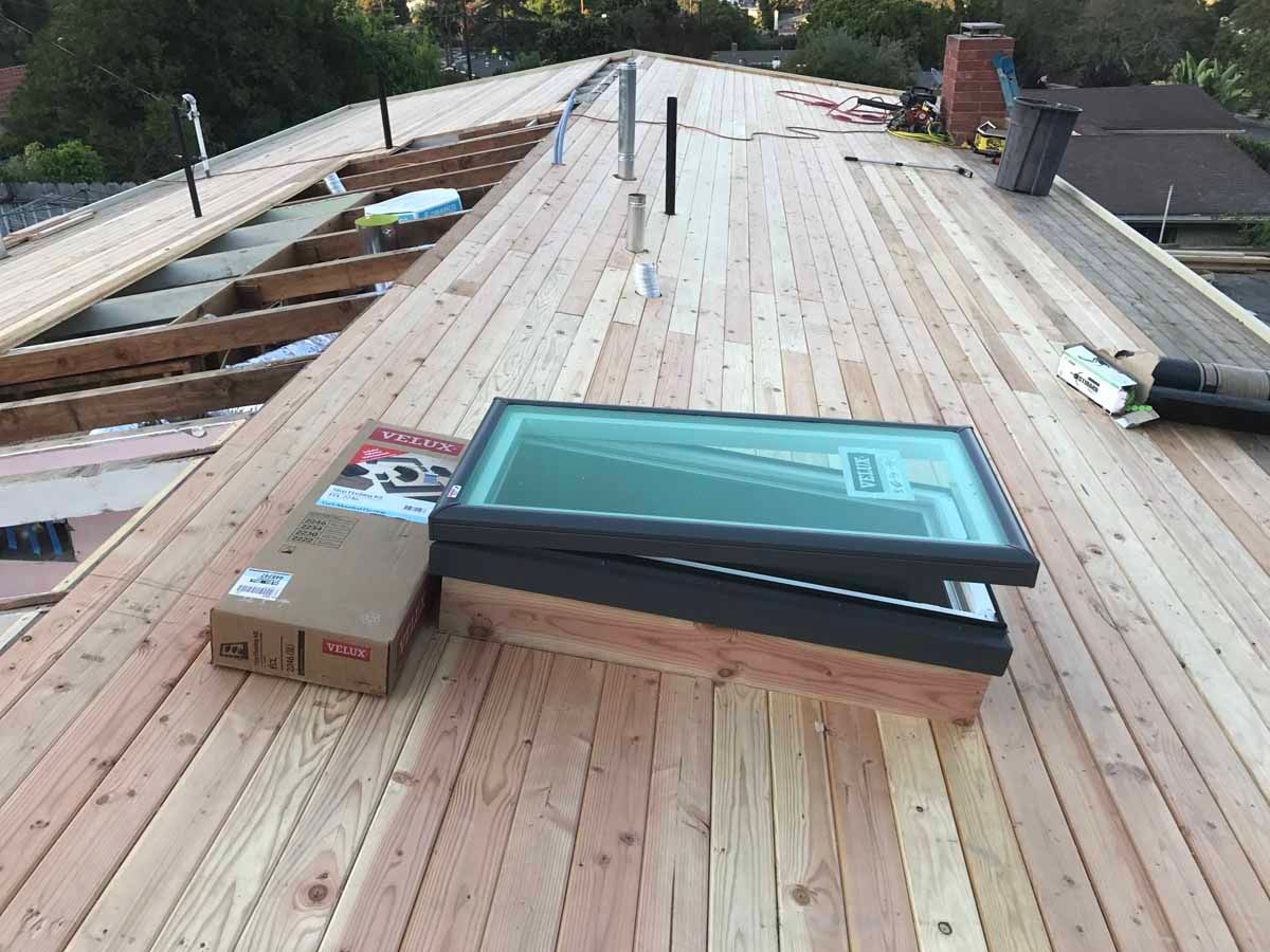 Roof under construction with stacked shingles and boxes on a wooden roof deck
