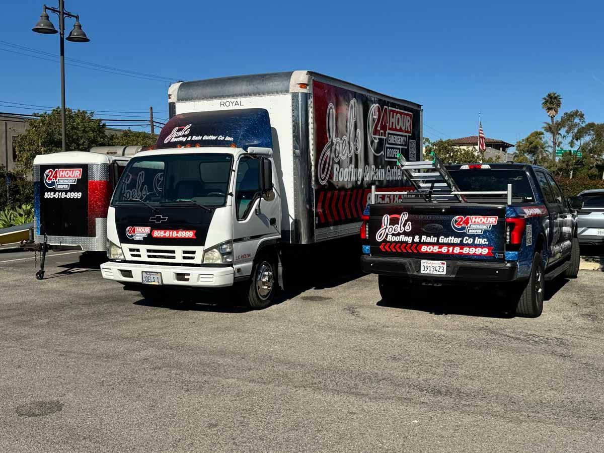 White truck and black pickup with red-and-white graphics parked in a lot under a clear blue sky