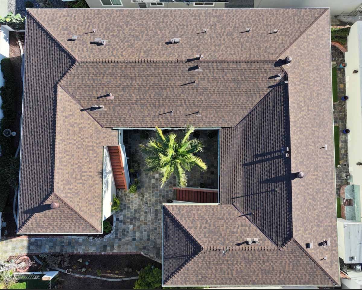 Aerial view of a tan-roofed house surrounding a small courtyard with a palm tree.