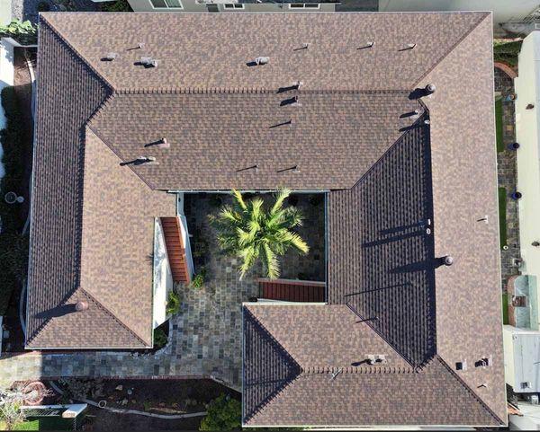 Aerial view of a tan-roofed house surrounding a small courtyard with a palm tree.