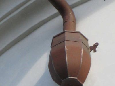 Brown ornate wall-mounted light fixture with a curved arm on a white ceiling
