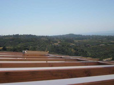 Wooden deck railing overlooking a green hillside under a clear blue sky