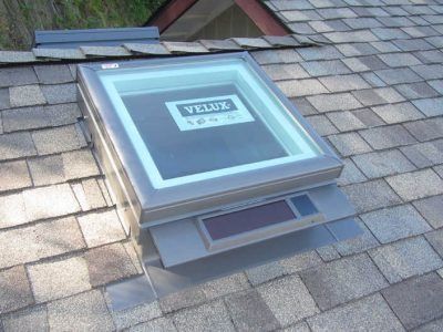 Skylight window with solar panels on a gray shingled roof