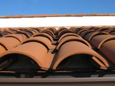 Close-up of terracotta roof tiles with curved ridges against a bright sky