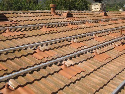 Terracotta tiled rooftop with several rows of roof tiles and small vents under daylight