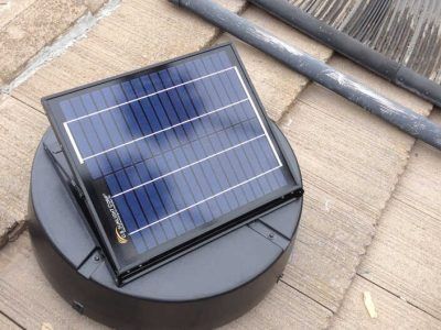 Solar-powered robot vacuum on a wooden deck, with a black body and blue solar panel top.