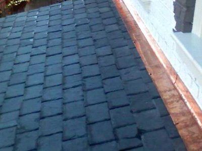 Dark slate roof shingles beside a light wall and copper trim