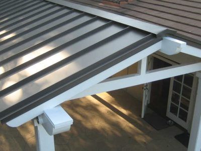 Covered patio with a metal roof and white support beams over a doorway