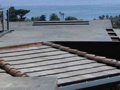 Flat rooftops with solar panels and ocean view in the background