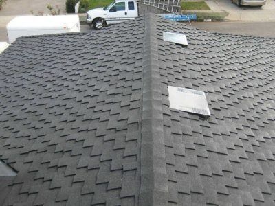 Roof with dark gray shingles and two roof vents, viewed from above