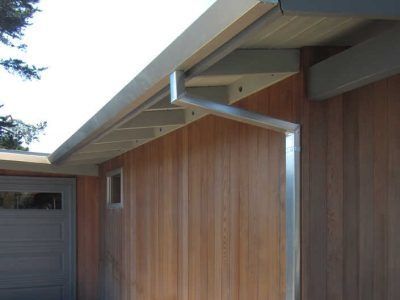 House exterior with wood siding, garage door, and sloped roof overhang