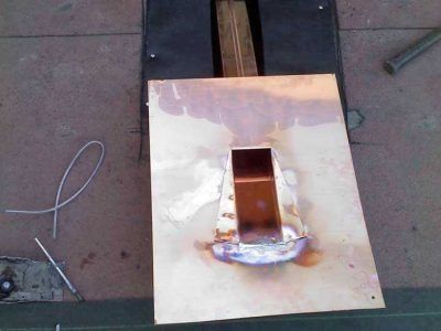 Metal sheet with a raised rectangular opening and a welded seam on a workshop floor