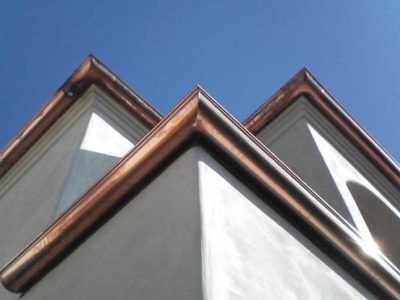 Copper-trimmed house roof peaks against a blue sky