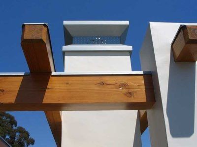 Wooden beams and white posts supporting a modern outdoor structure against a blue sky.