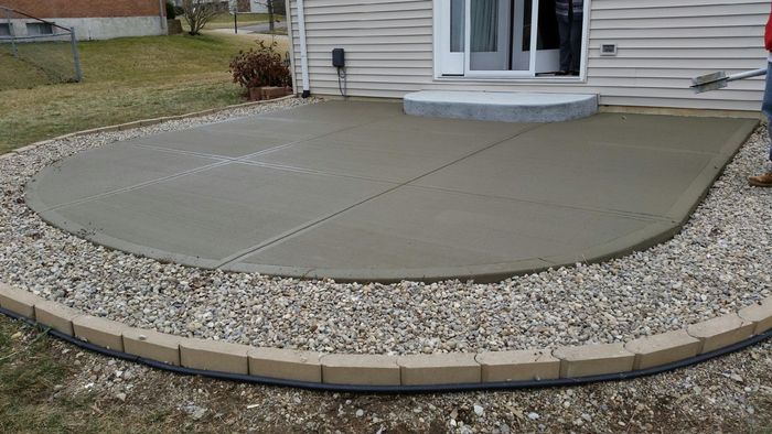 A concrete patio is being built in front of a house.