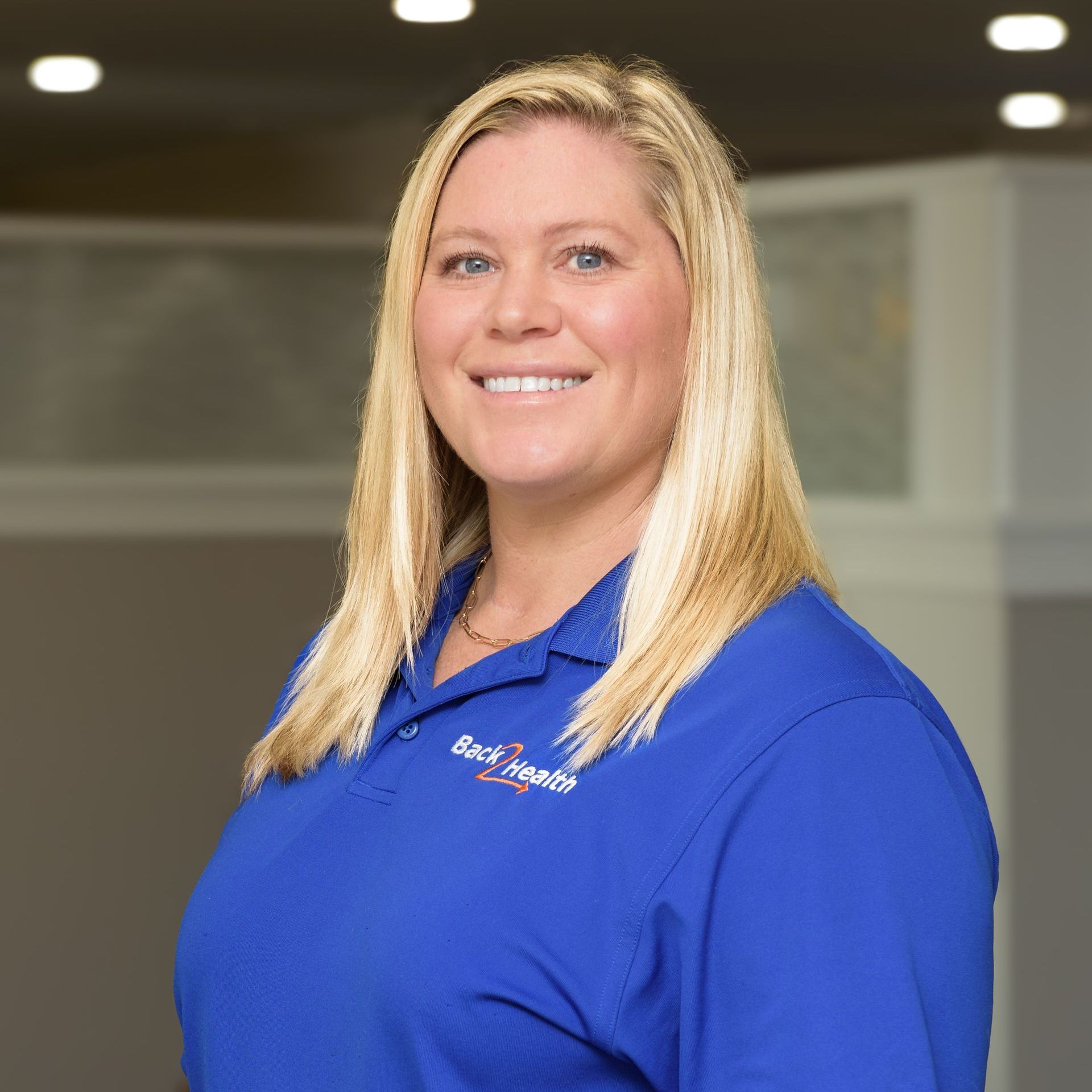 A woman in a blue shirt is smiling for the camera.