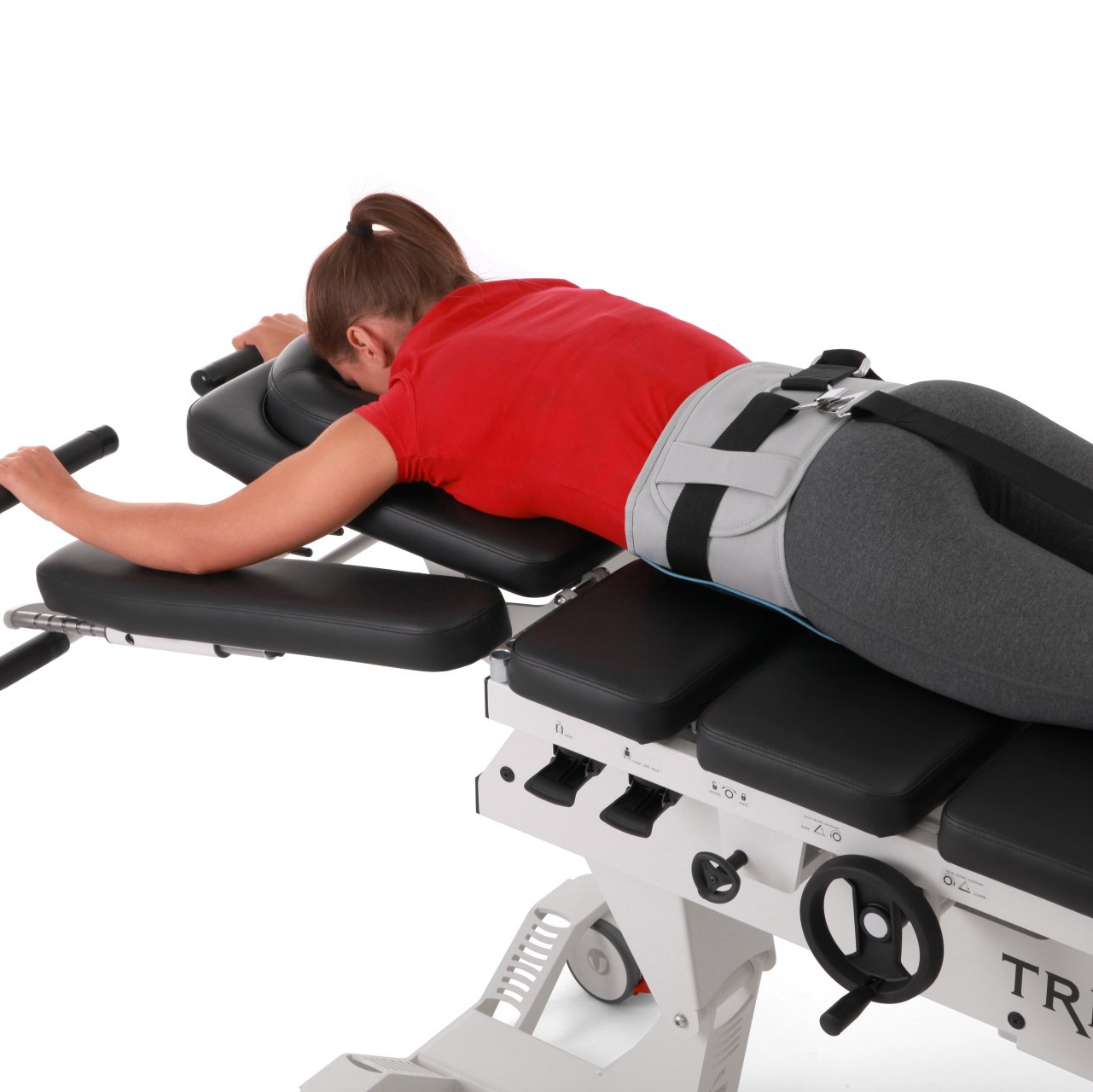 A woman in a red shirt is laying on a machine that says tr