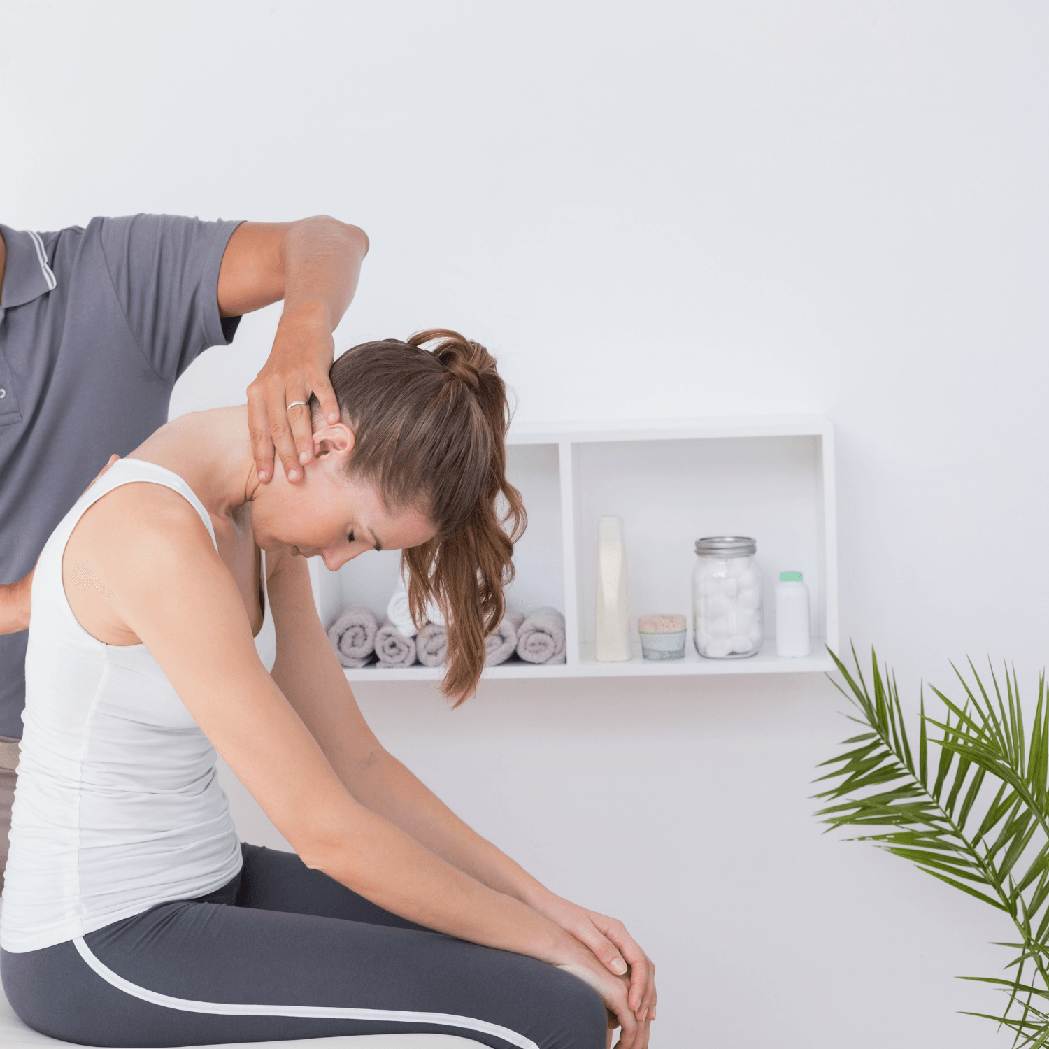 A man is stretching a woman 's neck while she sits on a table.