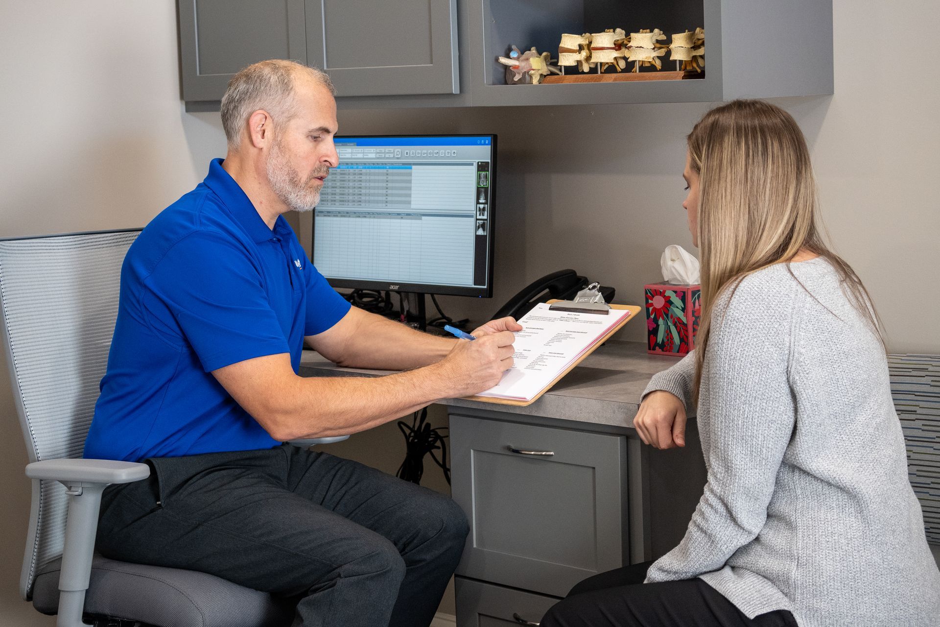 A man is sitting at a desk talking to a woman.
