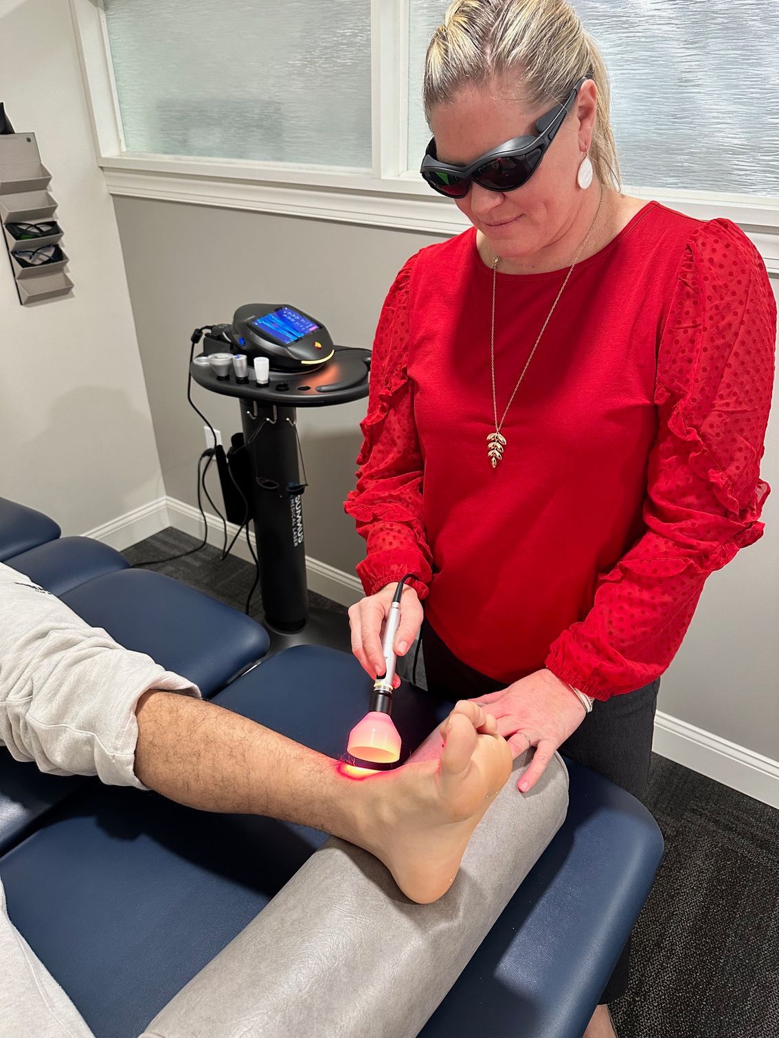 A woman is using a laser on a man 's foot.