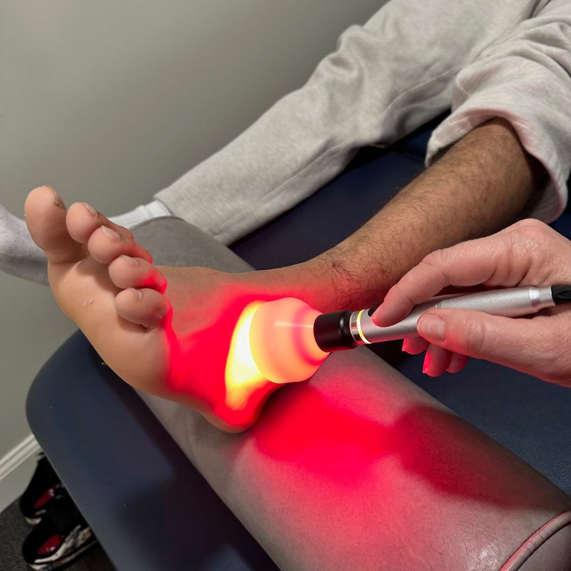 A person is getting a red light treatment on their foot