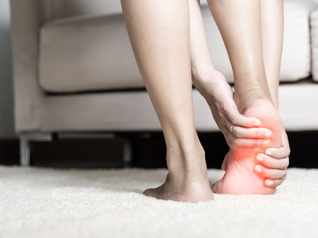 A woman is holding her foot in pain.