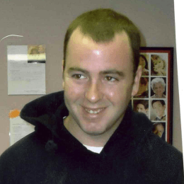 A man wearing a black hoodie smiles for the camera