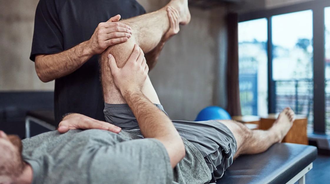 A man is getting a knee massage from a physical therapist. A man is getting a knee massage from a physical therapist.