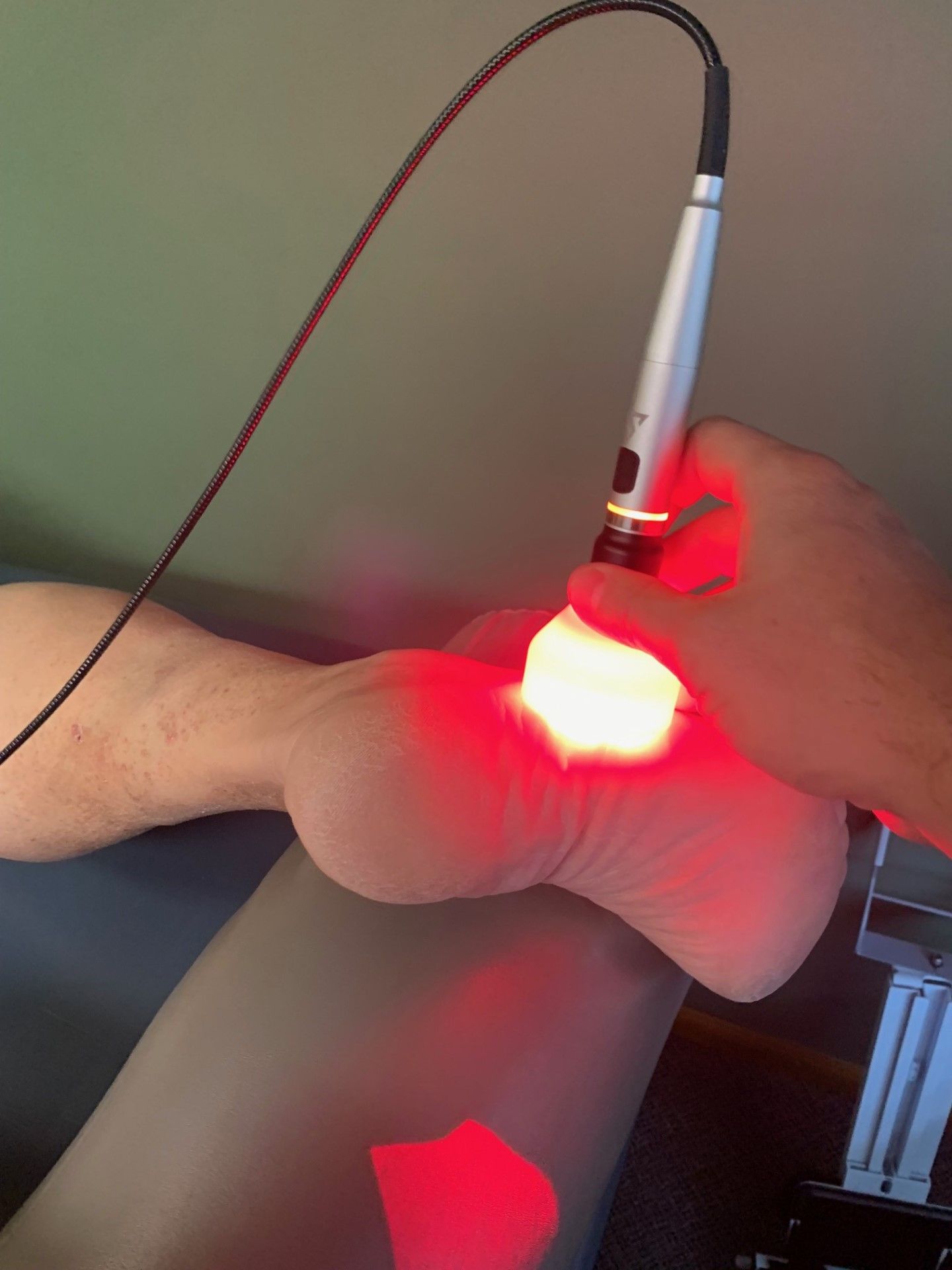A person is getting a red light treatment on their foot.