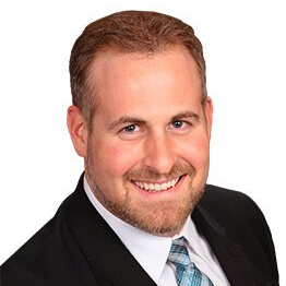 A man in a suit and tie is smiling for the camera.