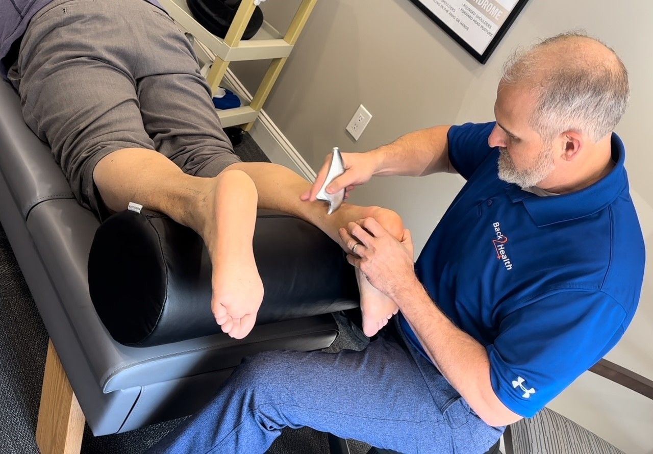 A man in a blue shirt is applying a bandage to a patient 's leg.