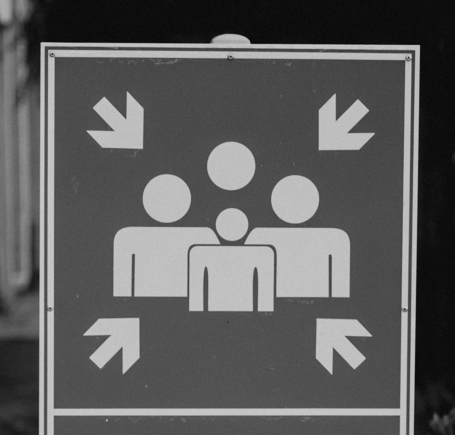 Panneau avec groupe de personnes et flèches convergeant vers l'intérieur.