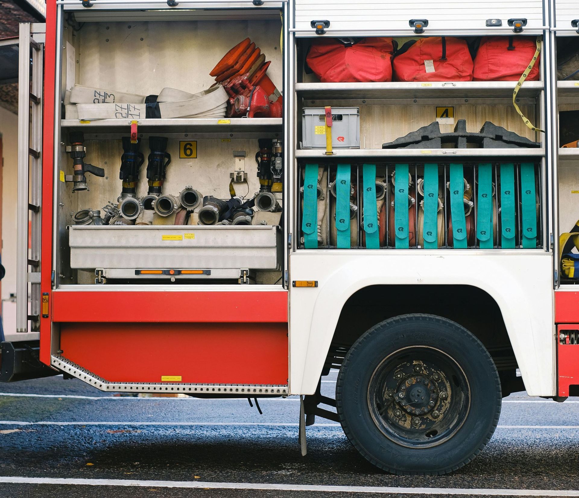 Vue latérale d'un compartiment de camion de pompiers rouge et blanc rempli d'équipement.