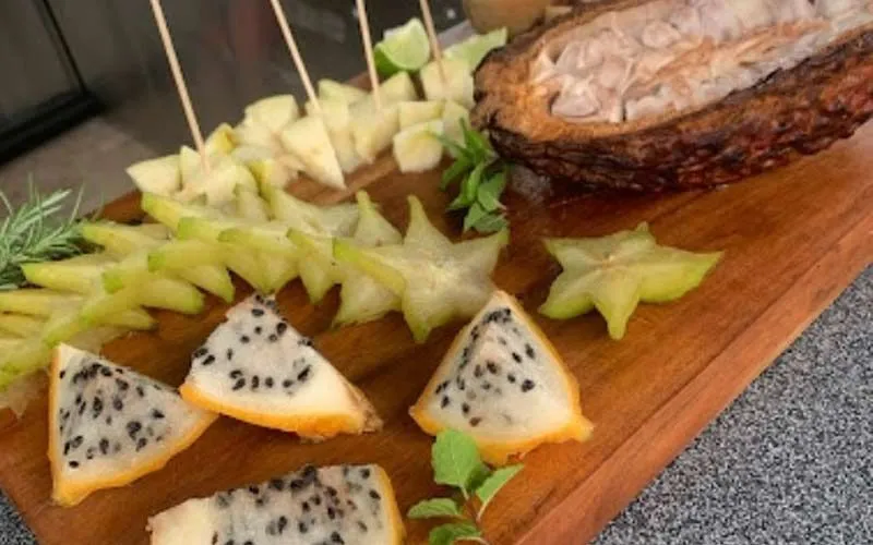A picture displays sliced tropical fruits on a wooden board