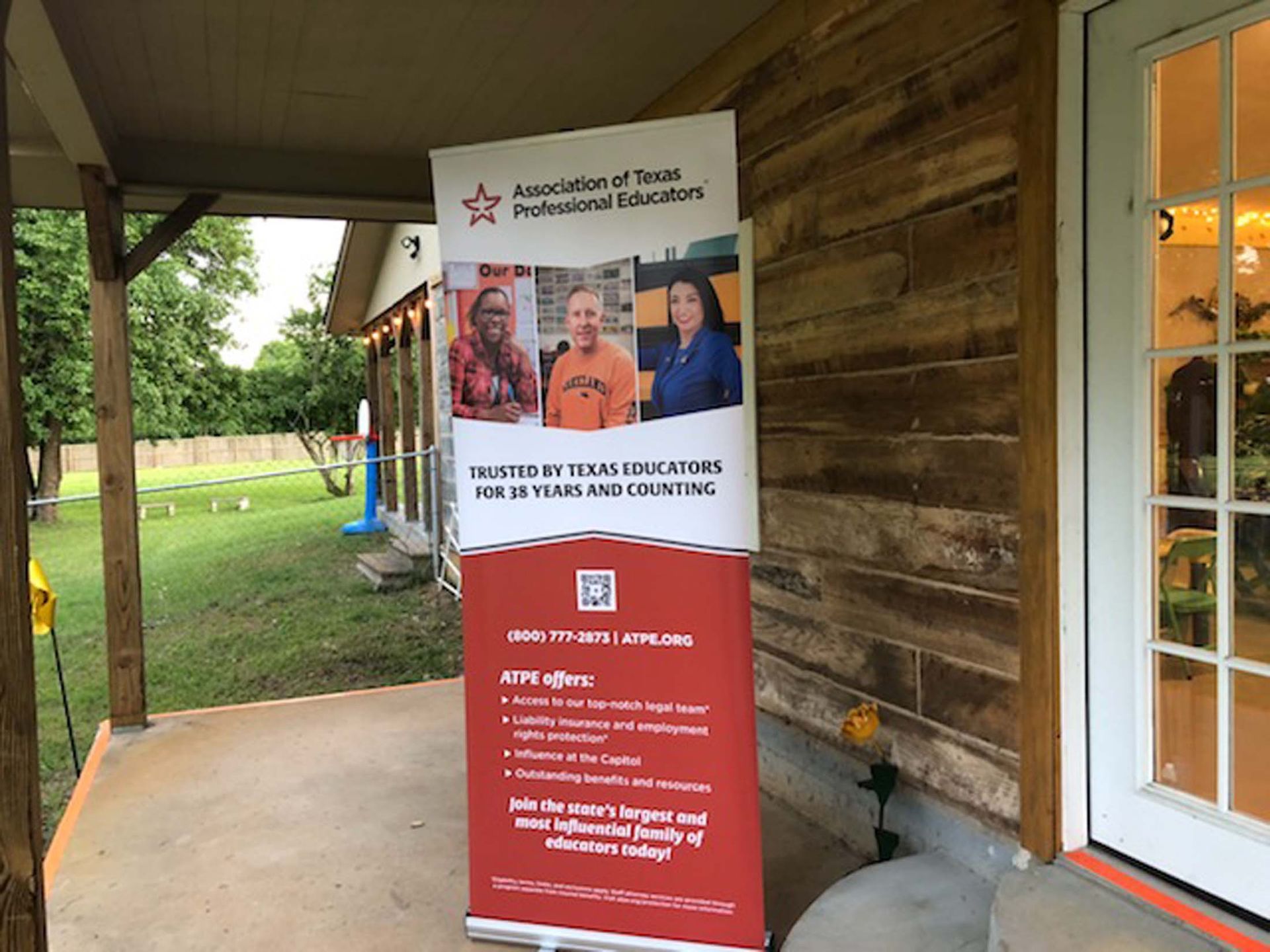 Red-and-white information banner under a covered porch beside a wooden building.