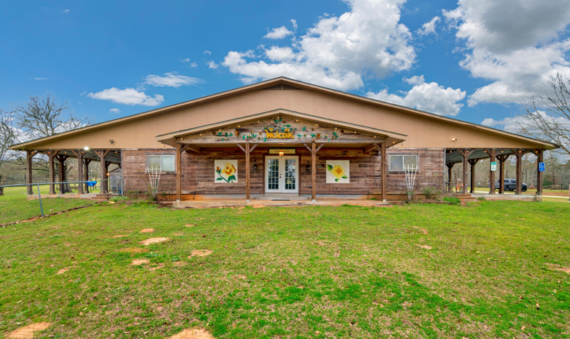 Brick community center with a covered porch and grassy front lawn under a blue sky