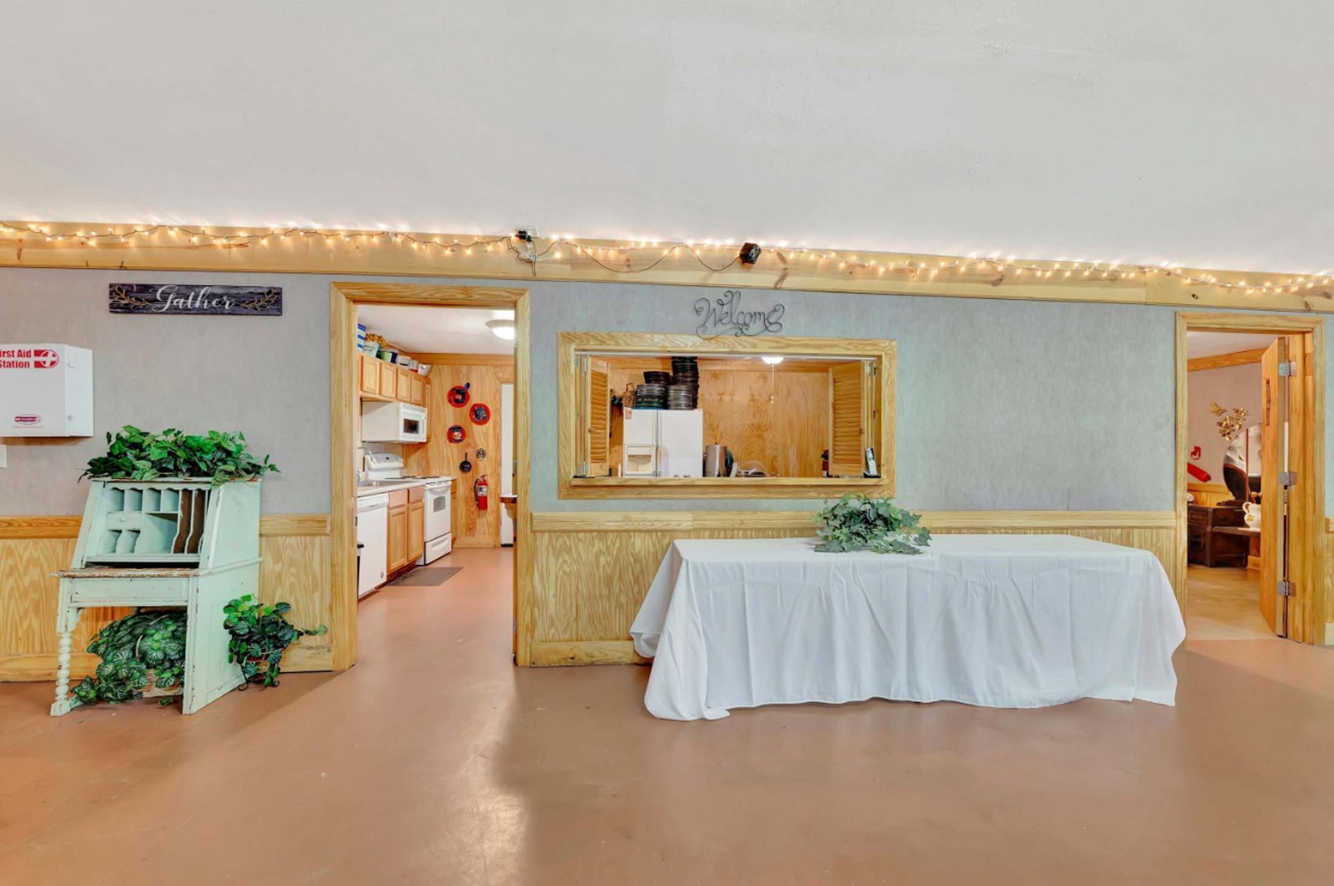 Bright banquet hall with a white tablecloth-covered table and service counter under warm lighting