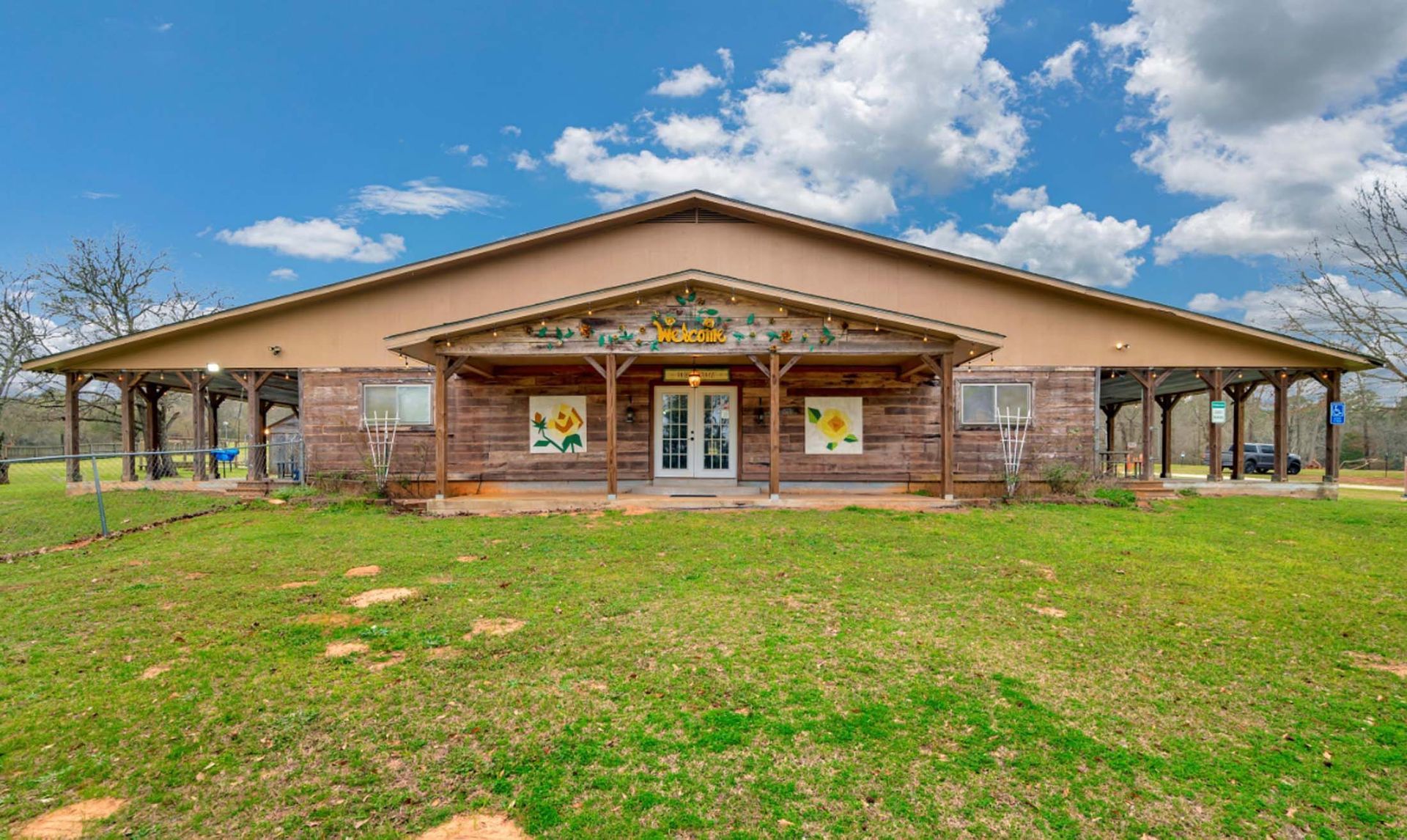 Brick community building with a covered porch and grassy lawn under a blue sky