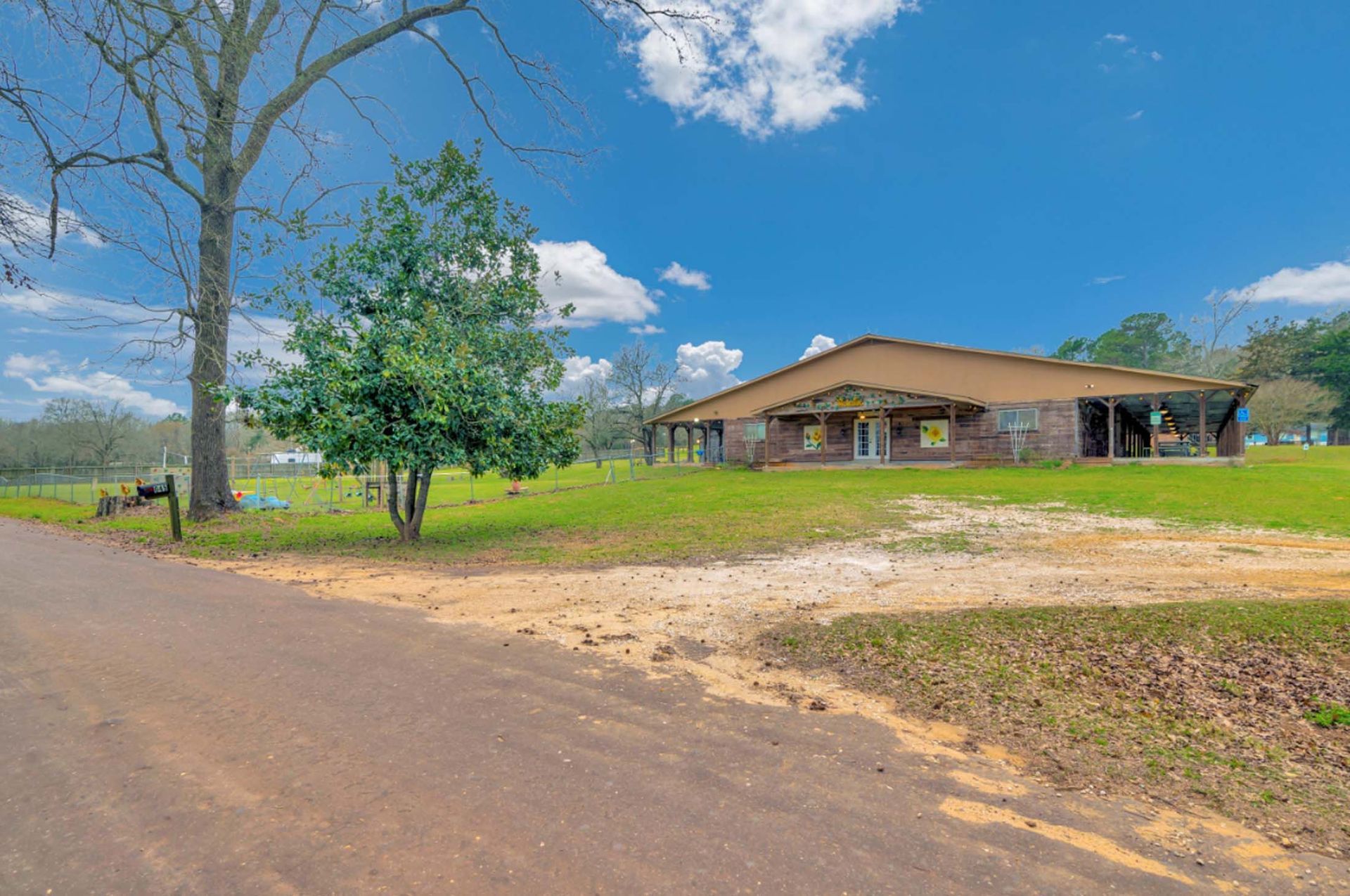 Rural house with a red roof beside a dirt road under a bright blue sky
