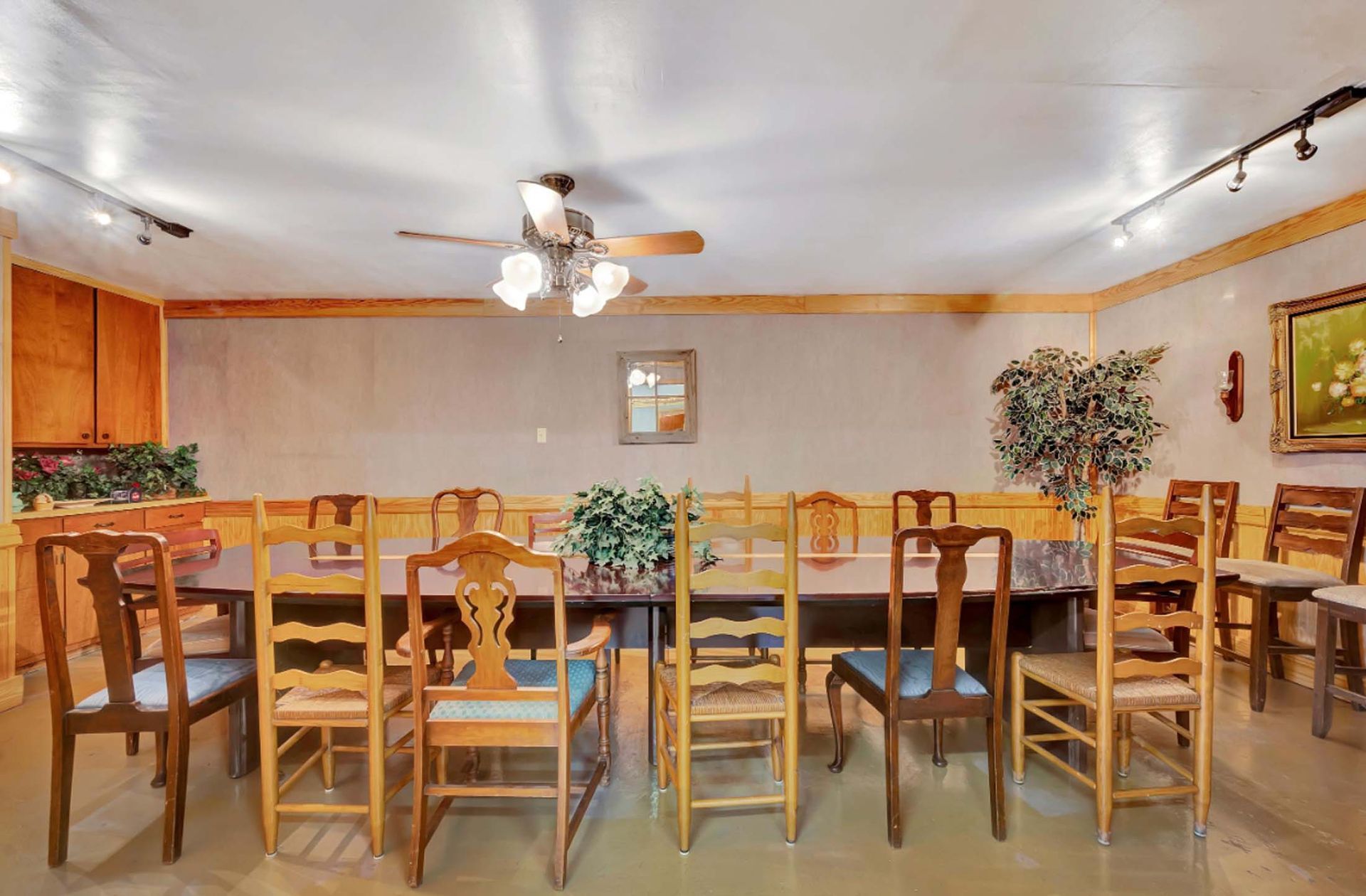 Empty dining room with wooden tables and chairs, ceiling fan, and warm lighting