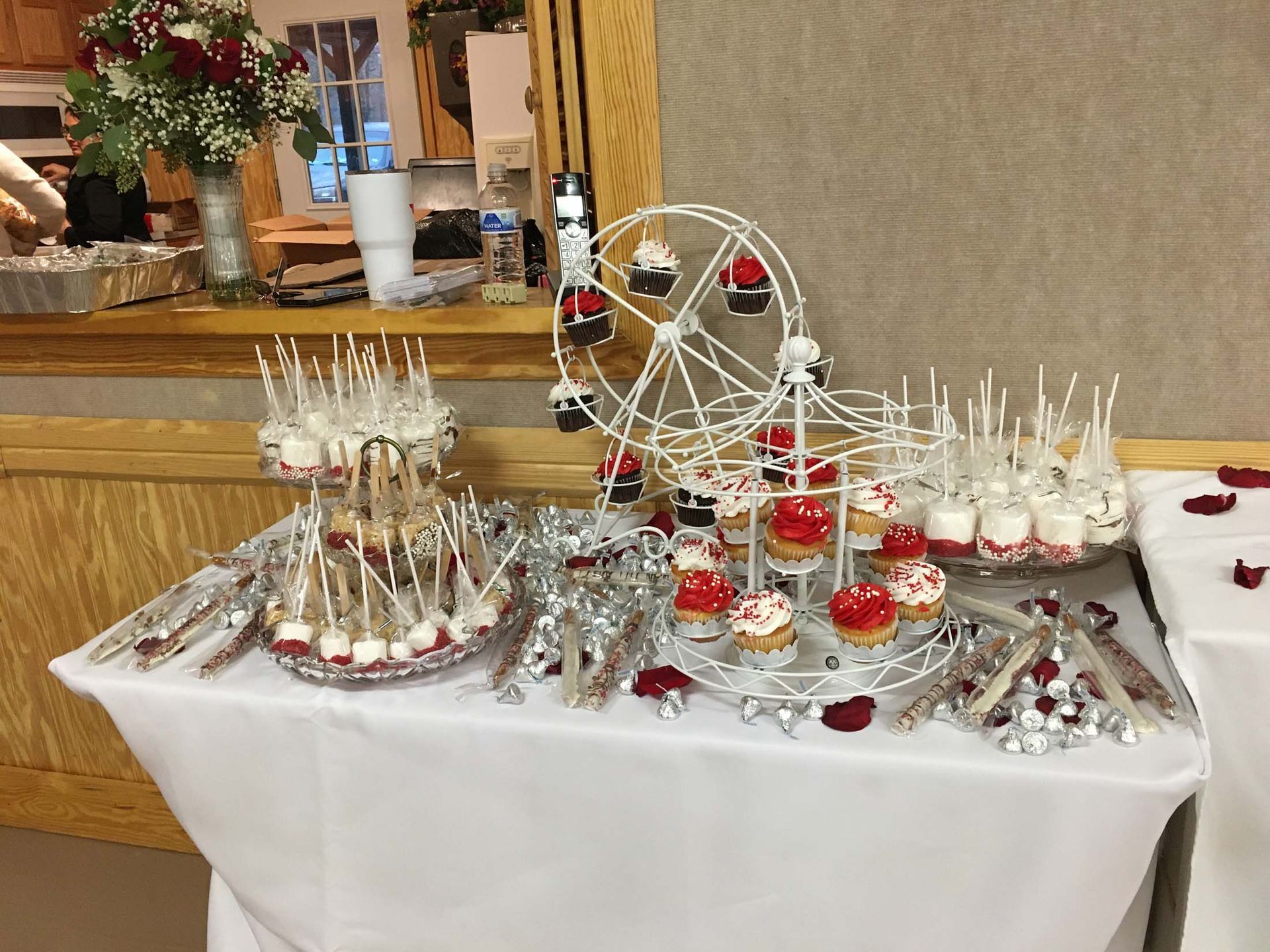 Dessert table with cakes, pastries, a Ferris wheel display, and red-and-white treats on a white cloth