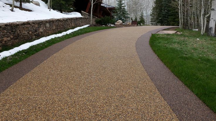 A resin bound pathway leading to a house with snow on the ground. Installed by Essex Resin driveways