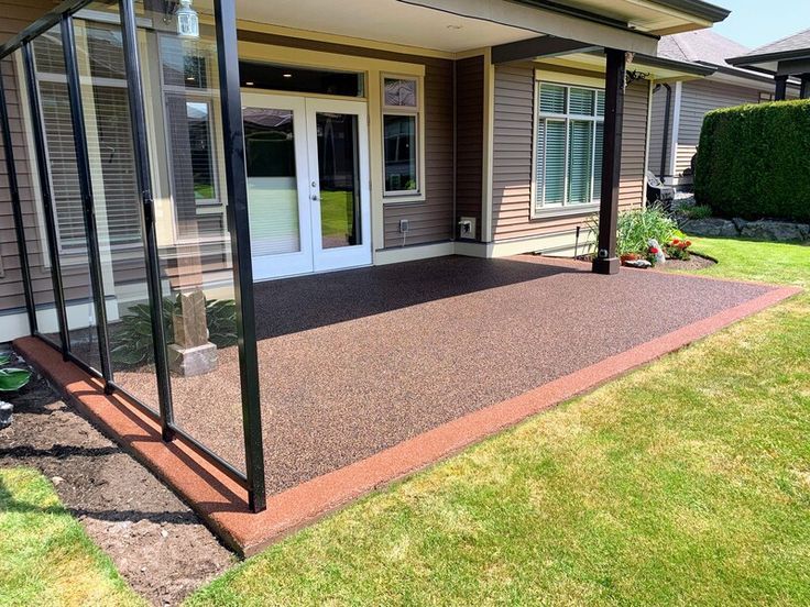 A resin patio with a screened in porch in front of a house in Essex/ Installed by Essex Resin driveways