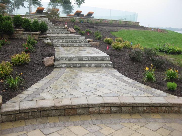 Stone steps and walkway leading uphill to a terrace with lounge chairs.