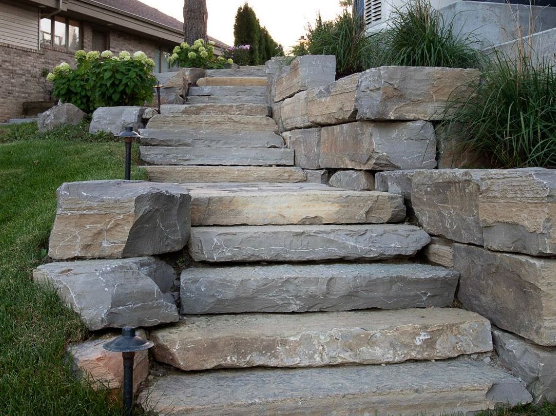 Stone steps leading upwards, flanked by stone retaining walls, grassy slope on either side.