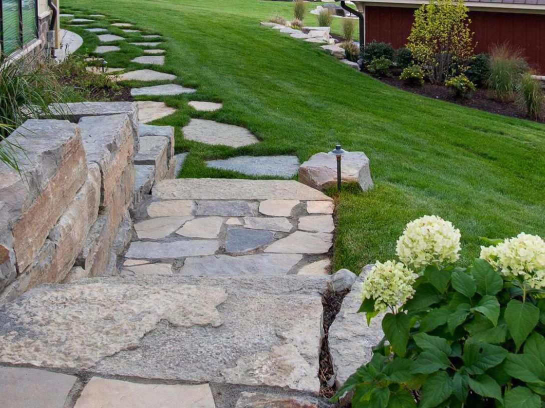 Stone steps and stepping stones ascend a grassy hillside.