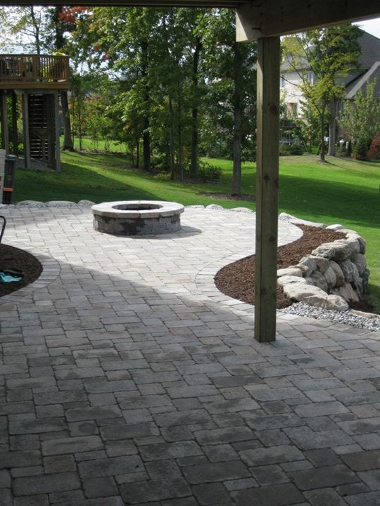 Stone patio with fire pit, wooden post, and a rock retaining wall.