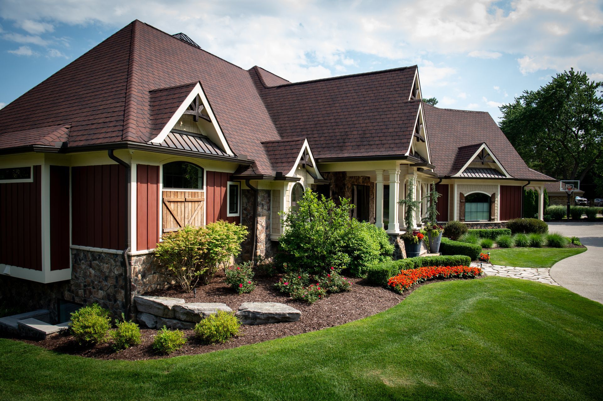 Red-sided house with brown roof and lush green lawn on a sunny day.