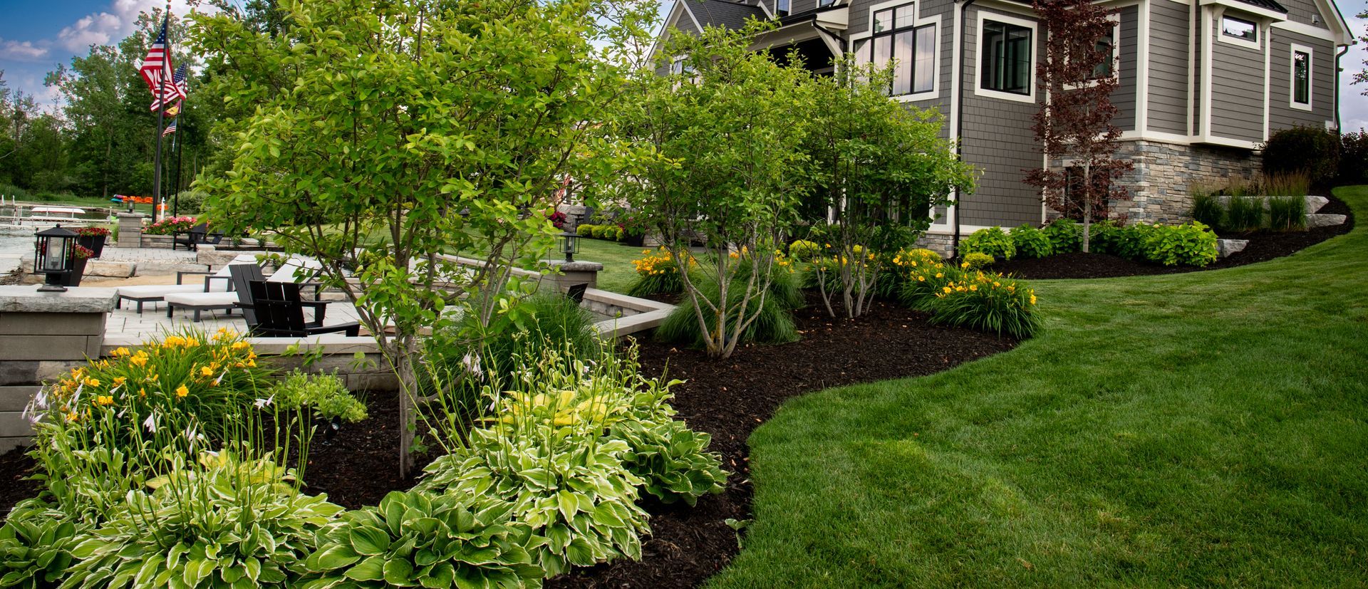 Landscaped yard with green grass, trees, and a house.